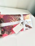 Premium Japanese-inspired floral gift wrap with gold accents and a white satin ribbon bow for Sam's Sakurapetals merchandise orders.